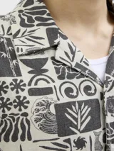 Camisa de manga corta con cuello resort y corte amplio. Presenta un estampado integral en tonos blanco y negro con motivos botánicos y marinos. Confeccionada en tejido liviano de viscosa y lino.