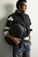 Mochila negra de acabado engomado con compartimento principal con cierre de cremallera. Cuenta con bolsillo interior con cierre, parte posterior acolchada con bolsillo oculto y banda de sujeción para equipaje, asa de mano y correas de hombro ajustables y acolchadas.