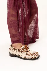 Zapato náutico de horma cuadrada confeccionado en cuero de pelo de vaca con estampado animal print. Presenta detalles de pasamanería en cuero descarne en el frente y laterales, cordones frontales y suela plana con pequeño taco.