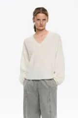 Sweater de punto en color blanco, confeccionado en una mezcla de lana y mohair. Posee un diseño de corte recto con escote en pico, mangas largas de sisa caída y acabados acanalados.