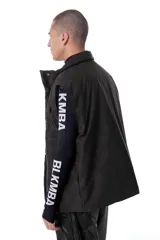 Chaleco negro con estampado de logos, cuello alto, cierre frontal con cremallera y broches a presión ocultos, bolsillos delanteros y cintura ajustable con cordón elástico. Interior de tafeta relleno de guata.