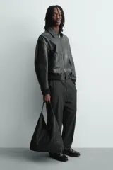 Bolso de hombro tipo hobo o shopper, color negro, con cuerpo de material trenzado. Posee un asa de hombro y un bolsillo interior con cierre de cremallera.
