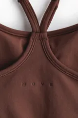 Top deportivo marrón de tejido funcional con tecnología DryMove, escote redondo y tirantes finos que se cruzan en la espalda. Presenta diseño sin costuras con paneles laterales acanalados y elástico en la base para mayor sujeción.