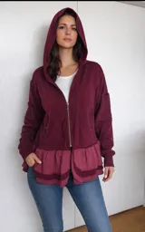 Hoodie con cierre frontal, confeccionado en algodón color bordó. Presenta capucha, bolsillos laterales con cierre y un diseño de doble volado en el ruedo que le otorga un estilo femenino y relajado.
