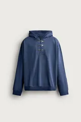Sudadera hoodie relaxed fit color azul, confeccionada en tejido de algodón. Presenta capucha y cierre frontal con alamares metálicos, manga larga y acabados en rib.
