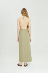 Vestido largo color verde oliva, con escote halter y lazo ajustable en la cintura. Presenta bolsillos laterales y corte recto.