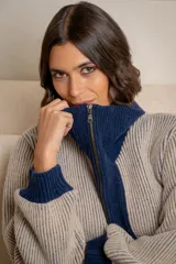 Campera de punto tipo cárdigan con cierre frontal de doble cursor, confeccionada en lana. Presenta un diseño bicolor con cuerpo en tono gris claro y detalles en azul marino en el cuello, la franja central, los bolsillos y los puños. Posee mangas largas con terminación ajustada y bolsillos frontales.