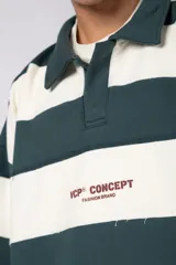 Buzo tipo polo de corte boxy, con diseño de franjas horizontales anchas en color verde oscuro y crema. Presenta cuello camisero, cierre frontal parcial y detalles de costuras desflecadas. Incluye logo bordado en el pecho.