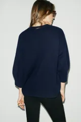 Chaqueta tipo cardigan de lana color azul marino, con cuello en pico, cierre frontal con botones y mangas abullonadas de largo tres cuartos.