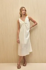 Vestido midi color crudo, sin mangas, con escote en V y detalle de nudo en el frente.