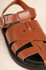 Sandalias bajas tipo gladiador, color negro, con tiras entrelazadas y hebilla metálica ajustable.