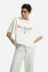 Remera oversized blanca de punto de algodón, con cuello redondo, mangas cortas y estampa tipográfica frontal con la inscripción "The Bellavista".