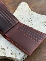 Billetera plegable de cuero color marrón rojizo, con el logo de Sierra Mora grabado en relieve en el exterior.