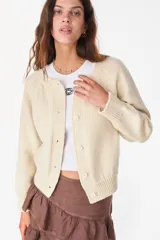 Cardigan de lana merino color crudo, de tejido de punto, manga larga y cierre frontal con botones.