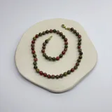 Collar de cuentas de piedra natural unakita de 6 mm, con separadores de nudos en hilo verde y cierre con baño de oro.