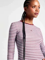 Camiseta de manga larga con cuello redondo, confeccionada en tejido acanalado con diseño de rayas horizontales en tonos claros y bordó. Presenta un pequeño bordado decorativo en el centro del pecho.