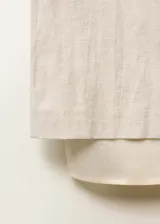 Falda midi de diseño recto y tiro medio, confeccionada en una mezcla de algodón y lino. Presenta cintura con elástico, abertura posterior en el bajo y un forro interior visible de ramio que sobresale del ruedo.