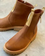 Botas de cuero color blanco con suela chunky y detalles en tono tostado, con cierre lateral y tirador en la parte trasera.