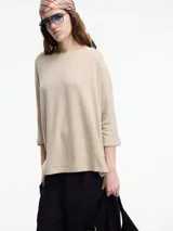 Sweater beige de mangas 3/4, con fit amplio y largo más pronunciado en la parte trasera.