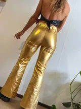 Pantalón dorado de tiro alto, corte ajustado hasta la rodilla y acampanado con aberturas en el ruedo.