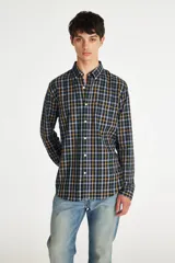 Camisa de manga larga con cuello abotonado y bolsillo frontal. Presenta un diseño de cuadros en tonos azul marino, verde y amarillo, con el distintivo tag rojo de la marca en el bolsillo.