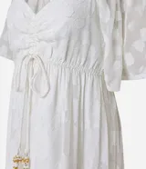 Vestido largo evasé de crepé blanco con textura y volados. Tiene escote corazón, elástico en la cintura, lazo con cordón y borla en las puntas, y mangas cortas.