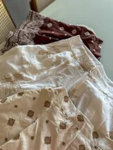 Shorts de tiro alto color marrón con estampado de pequeños rombos blancos y un borde ancho con diseño de encaje o bordado estilo paisley en blanco.