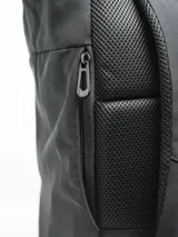 Mochila negra con cierre superior enrollable y hebilla de plástico. Cuenta con un bolsillo frontal con el texto "FORUM INDUSTRIES CO." y un parche en forma de diamante en la parte inferior. Tiene un bolsillo lateral con cierre.
