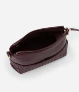 Bolso bandolera pequeño color borgoña, confeccionado en poliuretano con detalle texturizado tejido en la parte inferior. Cuenta con correa transversal ajustable, cierre de cremallera y bolsillo frontal con botón.