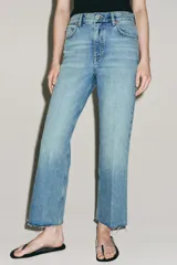 Jeans cropped flare de tiro medio color celeste, confeccionados en denim con efecto lavado. Presentan diseño de cinco bolsillos, trabillas para cinto, raya planchada al frente y bajo desflecado con terminación evasé. Cuenta con cierre frontal de cremallera y botón metálico.