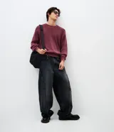 Pantalón de jean modelo super baggy, de corte holgado y tiro alto. Presenta costuras laterales con detalles deshilachados, cierre tradicional con botón y bolsillos funcionales.