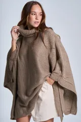 Poncho tejido color beige, con cuello alto y corte asimétrico.