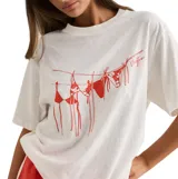 Remera de corte oversized color blanco, con cuello redondo y mangas cortas. Presenta un estampado gráfico en color rojo en el frente que ilustra bikinis colgados en una soga.