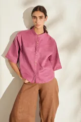 Camisa de lino color fucsia, con cuello mao, mangas cortas holgadas y cierre frontal con botones de madera. Cuenta con bolsillos frontales en el pecho.