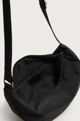 Bolso de hombro de nylon color negro, con diseño curvo y cierre de cremallera en el compartimento principal. Cuenta con asa ajustable para llevar al hombro y bolsillo interior con cierre.