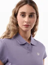 Chomba color lila de corte slim confeccionada en tejido de piqué suave y transpirable. Presenta cuello tipo chomba, cartera de dos botones, logo de Tommy Hilfiger bordado en el pecho y bandera de Tommy Hilfiger bordada en la manga.