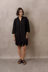 Camisola negra de silueta amplia, manga larga y diseño con bordados sutiles al tono, cuello camisero y cierre frontal de botones.