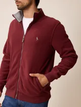 Campera de polar bordó con cierre frontal completo, cuello alto y puños elásticos. Presenta un diseño liso con logo bordado en el pecho.