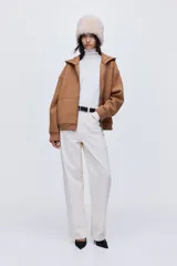 Campera con capucha forrada, confeccionada en tejido efecto neopreno color tostado. Presenta hombros caídos, cierre frontal, costuras visibles delanteras, bolsillos laterales discretos y terminaciones en rib en puños y bajo.