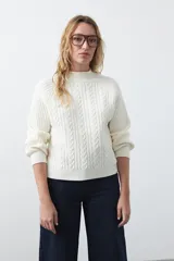 Polera de punto color marrón, con cuello alto y diseño de trenzas verticales en el frente y tejido acanalado en las mangas. Presenta mangas raglán y terminaciones acanaladas en puños y ruedo.