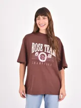 Remera de corte oversize color beige, con cuello redondo y mangas cortas. Presenta un estampado frontal con la frase 'Amore Mio', un dibujo de dos cerezas y la leyenda 'South Tuscany Italy'.