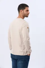 Remera de manga larga en color azul oscuro, con cuello redondo y estampado frontal de paisaje montañoso. Presenta un pequeño parche decorativo en la manga.