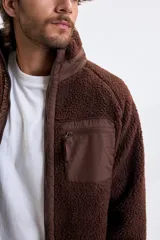 Campera de sherpa color marrón con cierre frontal completo, cuello alto y bolsillo en el pecho con cierre.