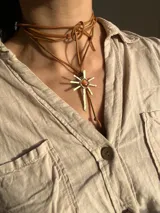 Gargantilla con cordones de gamuza marrón y dije de sol dorado con piedra de ágata en el centro.
