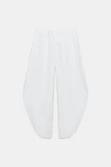 Pantalón tiro medio de lino 100% color blanco, con cintura elástica ajustable mediante cordones y bajo redondeado con aberturas laterales.