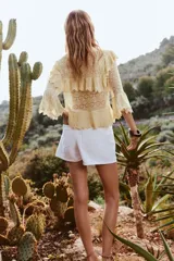 Falda pantalón corta de tiro alto color blanco, con bolsillos delanteros y traseros. Cierre frontal cruzado con cremallera oculta y botón metálico.