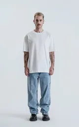 Remera oversize de algodón premium color blanco tiza, con cuello redondo rib al tono y hombros caídos.