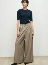 Pantalón de vestir color beige, de corte wide leg y tiro alto, con pinzas frontales y cierre de botón y cremallera.