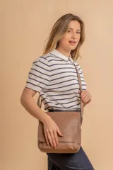 Bandolera de diseño simple con tapa frontal, confeccionada en material símil cuero. Cuenta con correa ajustable, división interna y bolsillos internos para mayor organización.