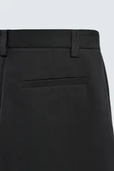Pantalón de corte wide fit confeccionado en tejido con mezcla de lyocell. Presenta pliegues frontales dobles, bolsillos laterales y bolsillos traseros de vivo. Cierre frontal con cremallera y gancho metálico oculto.